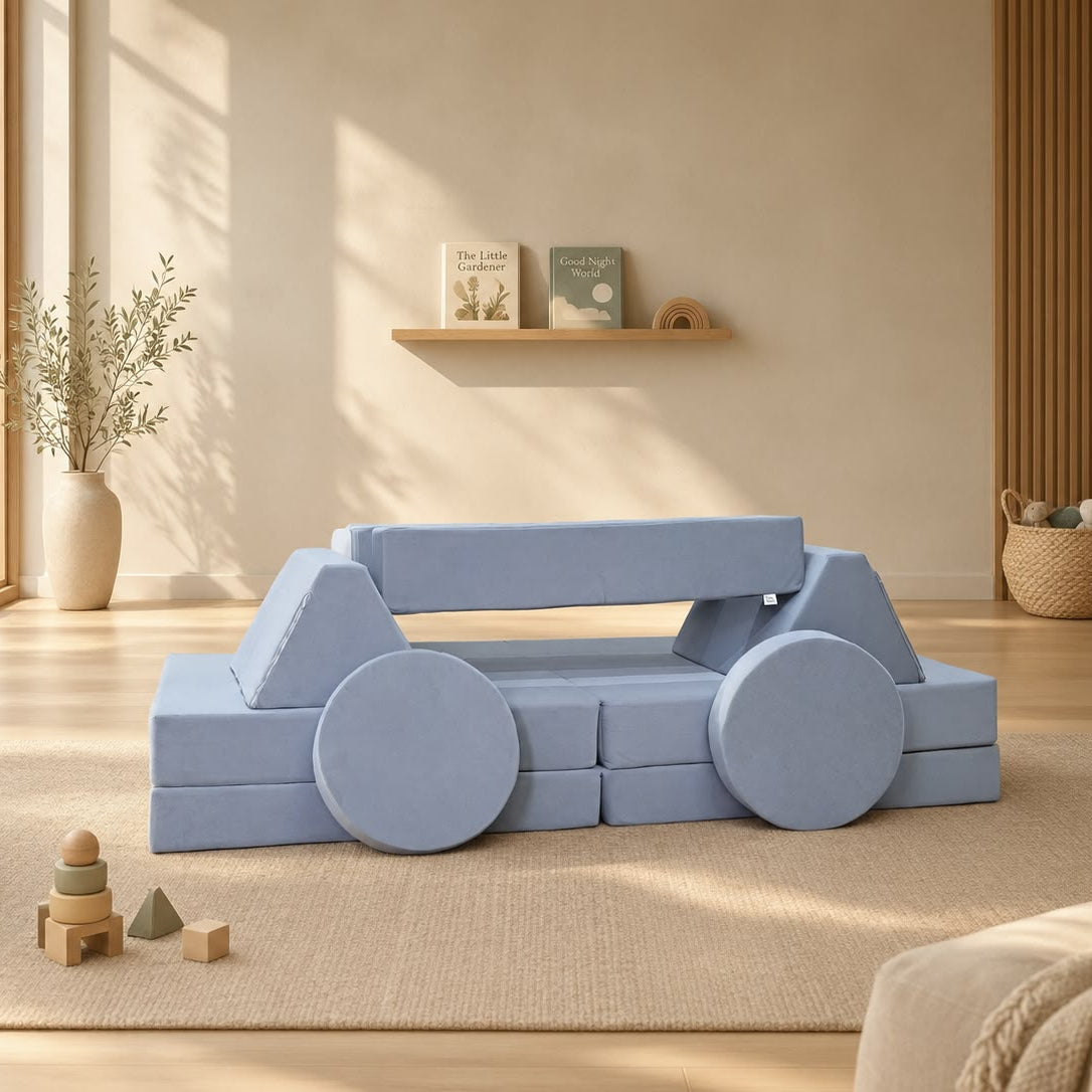 A light blue modular foam play couch shaped like a car, styled in a warm, modern children's room with wooden floors, a beige rug, and toys.
